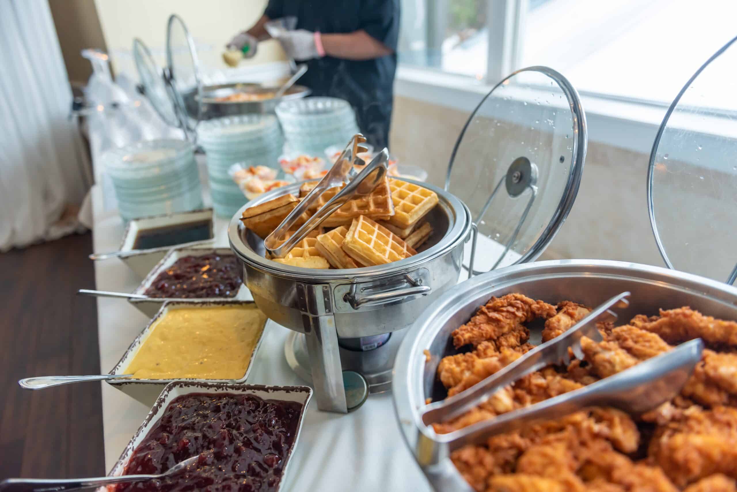 A high angle shot of fried chicken and waffles and jams on a table