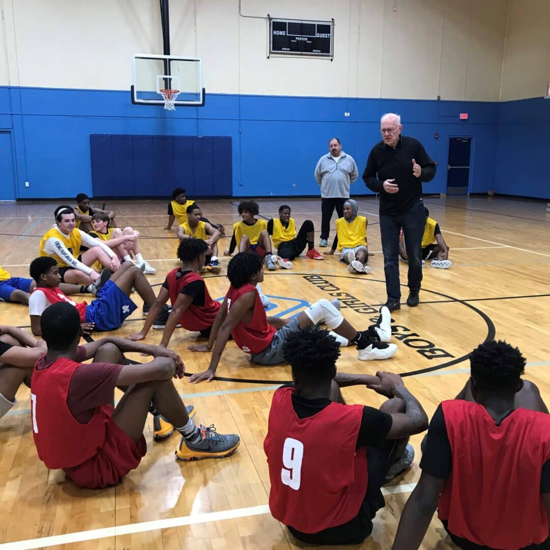 A Men Serving God volunteer coaching and speaking to young athletes during a basketball mentorship session in a gym